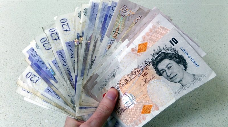 A hand holding British money